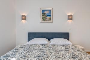a bed with two pillows and a picture on the wall at Centrally located apartments, free parking in Trogir