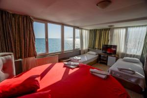 a bedroom with a red bed with a view of the ocean at Kutlugun Sahil Otel in Akçay