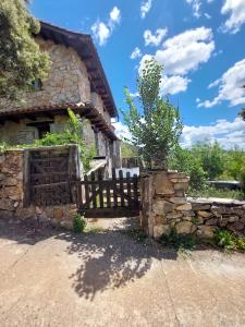 an old house with a wooden gate and a stone wall at Las Peonías Casa Rural in Almiruete