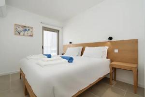 a large white bed with two towels on it at Dália modern apartment Five minutes to beach in Luz +33 photos