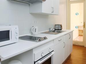 cocina blanca con fregadero y microondas en Roc Portonova Apartaments, en Palmanova
