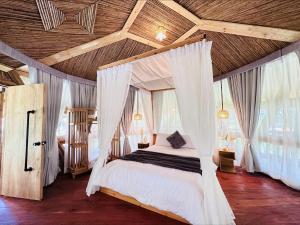 a bedroom with a canopy bed with white curtains at Alina Farm Resort- Two Bedroom Villa in Manolo Fortich +33 photos