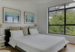 a white bedroom with a large bed and a window at Lv Guest house mafikeng in Mahikeng