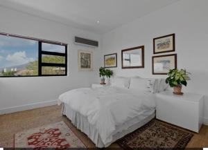 een witte slaapkamer met een groot bed en een raam bij Lovicc Guest house mafikeng in Mahikeng