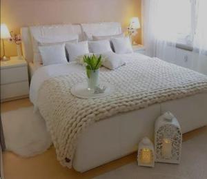 een wit bed met een vaas met bloemen erop bij Lovicc Guest house mafikeng in Mahikeng