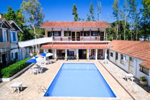 a house with a swimming pool in front of a house at VELINN Pousada Cesar in Santo Antônio do Pinhal
