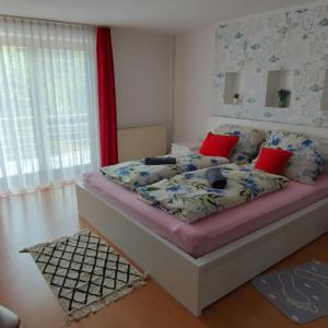 a bedroom with a bed with red pillows at Balatoni Aranyparti Apartmanok in Siófok