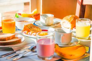 a table topped with plates of breakfast foods and drinks at VELINN Pousada Cesar in Santo Antônio do Pinhal