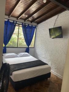 a bedroom with a bed with blue curtains and a tv at Blue Coast Hostal in Medellín