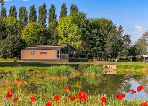 a house with red poppies in front of a lake at Bredon View in Pershore