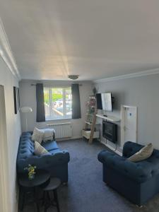 ein Wohnzimmer mit 2 blauen Sofas und einem TV in der Unterkunft Ghyll Rigg in Bowness-on-Windermere