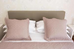 1 cama con almohadas blancas y almohadas rosas en Casa Esposito, en Nápoles