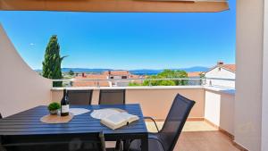 - Balcón con mesa y sillas y botella de vino en Modern Apartment Ana, en Malinska