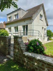 a white house with a fence and some flowers at Le gîte de la tortue in Bayeux