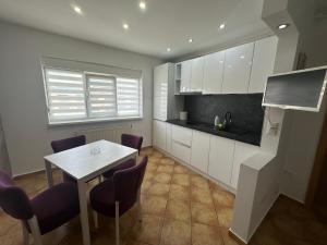 a kitchen with a table and purple chairs at Apartamente Cugir in Cugir
