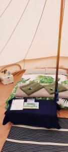 een bed in een tent met een bord erop bij Summit Camping Kit Hill Cornwall Panoramic Views Pitch Up or book Bella the Bell Tent in Callington