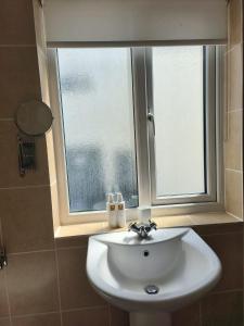 ein weißes Waschbecken im Bad mit Fenster in der Unterkunft Ghyll Rigg in Bowness-on-Windermere