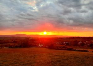 a sunset over a field with the sun in the sky at Summit Camping Kit Hill Rd Cornwall in Callington +24 photos
