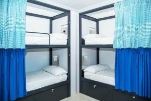 Habitación con 3 literas y cortinas azules. en Onefam Catedral, en Sevilla