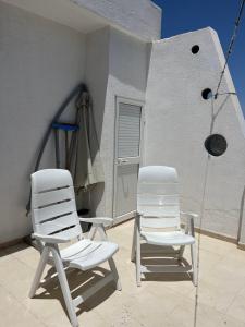 two white chairs sitting on a patio next to a building at Apartment Monastir Centre in Monastir
