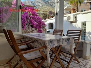 a table and chairs on a balcony with purple flowers at On the Beach Ivan Dolac in Ivan Dolac