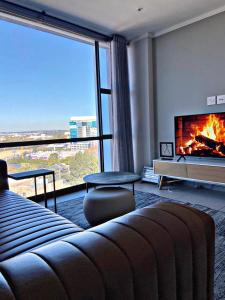 sala de estar con chimenea y ventana grande en Luxury Masingita towers 9th floor apartment, en Johannesburgo