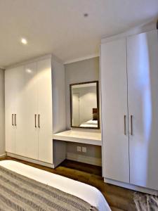 1 dormitorio con armarios blancos y espejo en Luxury Masingita towers 9th floor apartment, en Johannesburgo