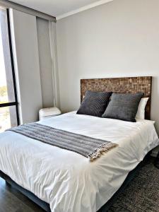 1 dormitorio con 1 cama blanca grande y ventana grande en Luxury Masingita towers 9th floor apartment, en Johannesburgo
