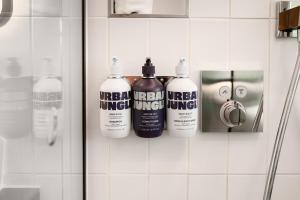 un gruppo di quattro prodotti per la pulizia su un muro del bagno di YOTELPAD London Stratford a Londra