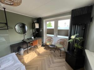 a bedroom with chairs and a desk and a window at Hotel de Pergola in Giethoorn