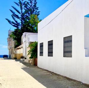 a white building with three windows on a street at Blue holiday in Oued Laou