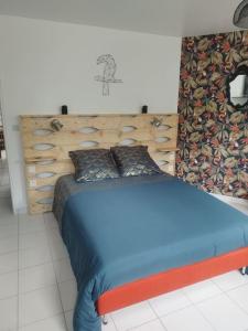 a bedroom with a blue bed with a wooden headboard at Plain-pied T1 patio et jardin in Trémuson