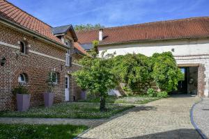 a brick building with a tree in the courtyard at Le Relais du Beffroi & SPA in Saint-Riquier