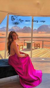 Una mujer con un vestido rosa sentada en un porche en Rum Mere luxury camp en Wadi Rum