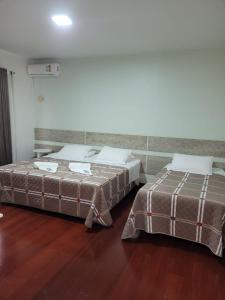 two beds sitting next to each other in a room at Hotel Vila Germânica in Blumenau