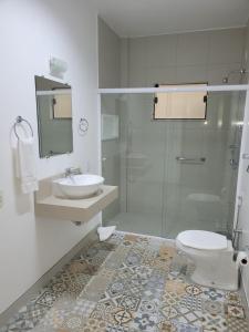 a bathroom with a toilet and a sink and a shower at Hotel Vila Germânica in Blumenau