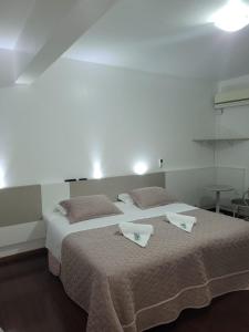 a bedroom with two beds with towels on them at Hotel Vila Germânica in Blumenau