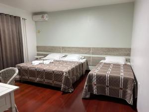 duas camas num quarto de hotel com em Hotel Vila Germânica em Blumenau