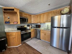 a kitchen with wooden cabinets and a stainless steel refrigerator at Stroll to Slopes, Village Area, Ski in-out MtLodge 308 in Snowshoe