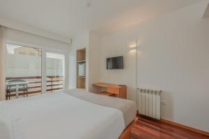 Costa Nova Hotel في كوستا نوفا: غرفة نوم بيضاء مع سرير وشرفة