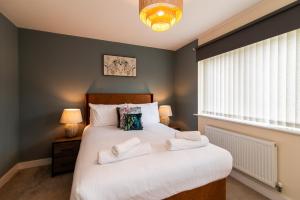 um quarto com uma grande cama branca e 2 toalhas em Spacious House Close to Royal Derby Hospital, Free Parking & Garden em Derby