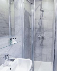 a white bathroom with a shower and a sink at Sinclair's Rooms in Southport