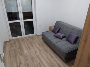 a couch with two purple pillows in a living room at Visočka Banja Apartmani in Arilje +6 photos