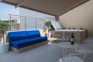 a blue couch on a balcony with a bottle of wine at Notos Boutique Apartments 3 with Private Jacuzzi in Heraklio