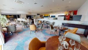 a restaurant with tables and chairs and a bar at Holiday Inn Cardiff City, an IHG Hotel in Cardiff