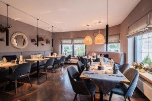 a dining room with tables and chairs and large windows at Hotel Guter Tropfen in Hagnau