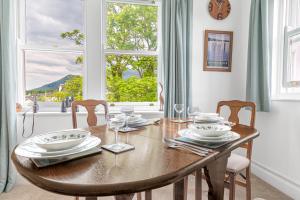 un tavolo da pranzo con sedie e una grande finestra di The Hytte, 19 Greta Grove House a Keswick