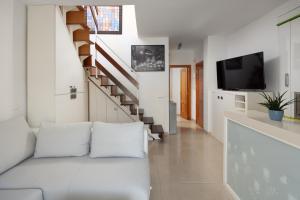 een woonkamer met een witte bank en een trap bij Ático el morche in Morche