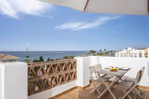 een balkon met een tafel en stoelen en de oceaan bij Ático el morche in Morche