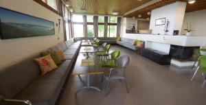 a restaurant with a long couch and chairs and a fireplace at Moldefjord Hostel in Molde